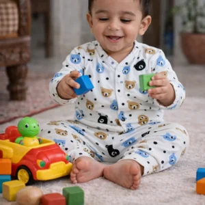 Smiling baby playing with colorful toys while wearing a soft cotton co-ord set with cute teddy bear and polka dot print