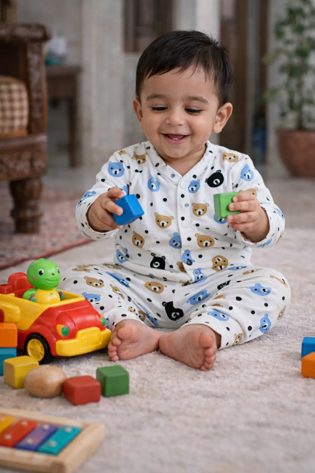 Smiling baby playing with colorful toys while wearing a soft cotton co-ord set with cute teddy bear and polka dot print