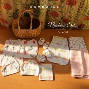 100% muslin cotton newborn baby gift set with jabla, nappy, bib, cap, mittens, booties, hooded towel and muslin cloth neatly arranged on a wooden table by Bamboree. All the prints have flower designs.